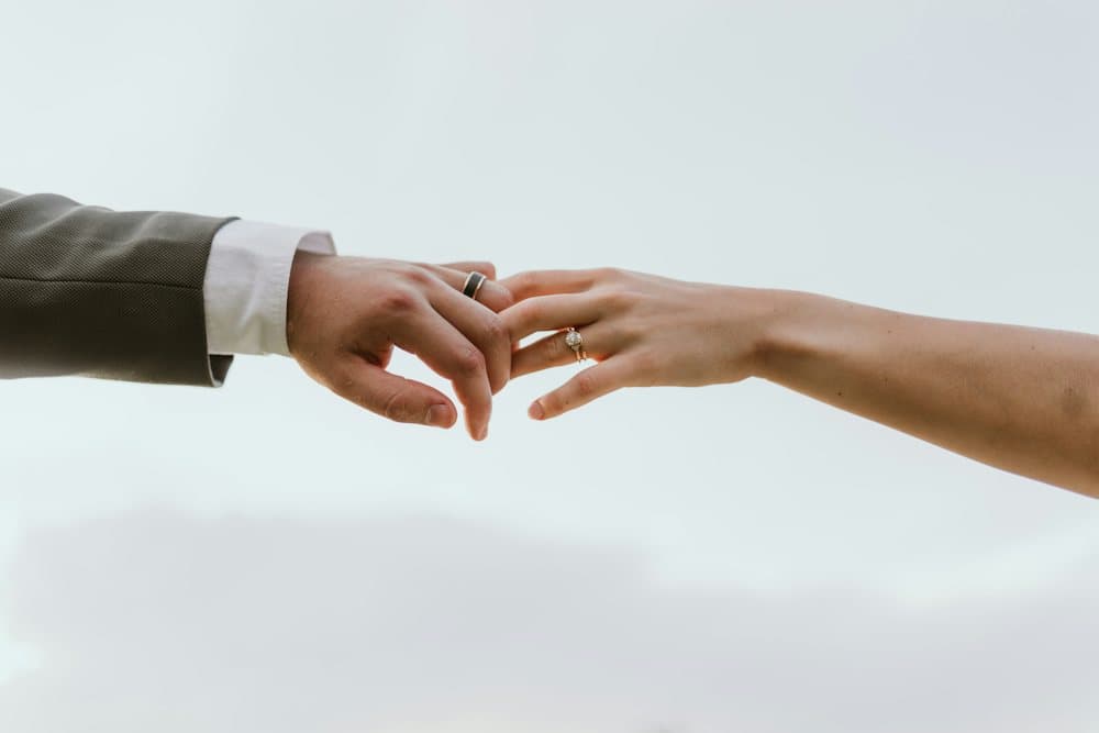 Hai bàn tay đeo nhẫn chạm nhẹ vào nhau trên nền trời